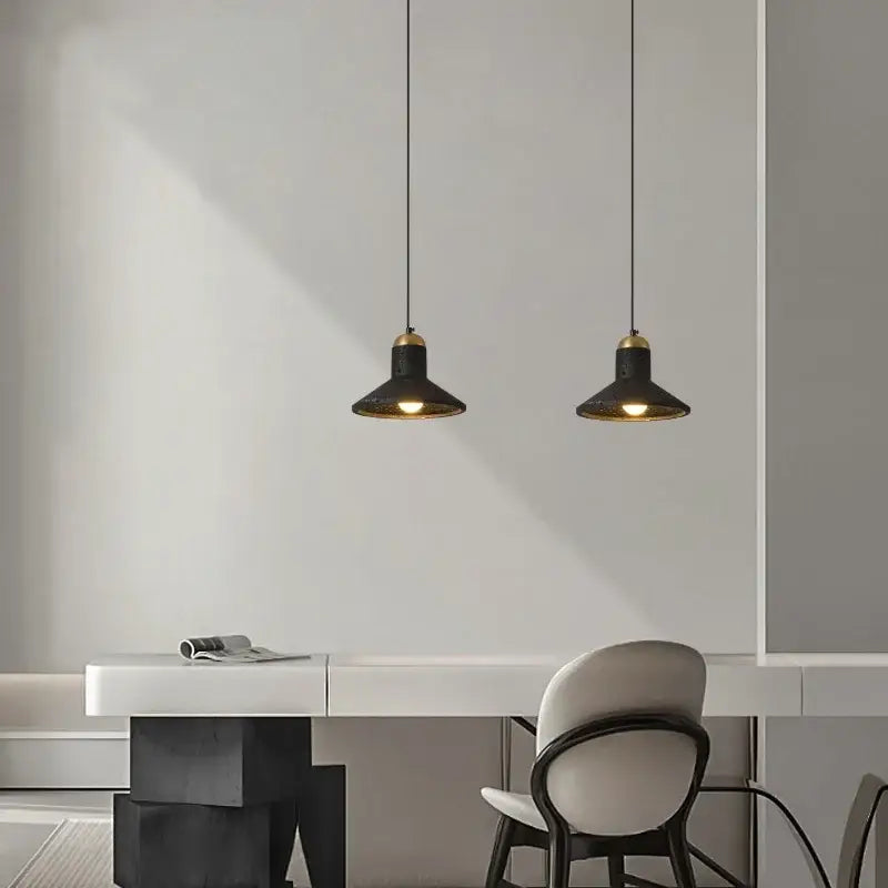 Two black travertine led pendant lights with brass accents hang above a minimalist white desk decorbites black travertine
