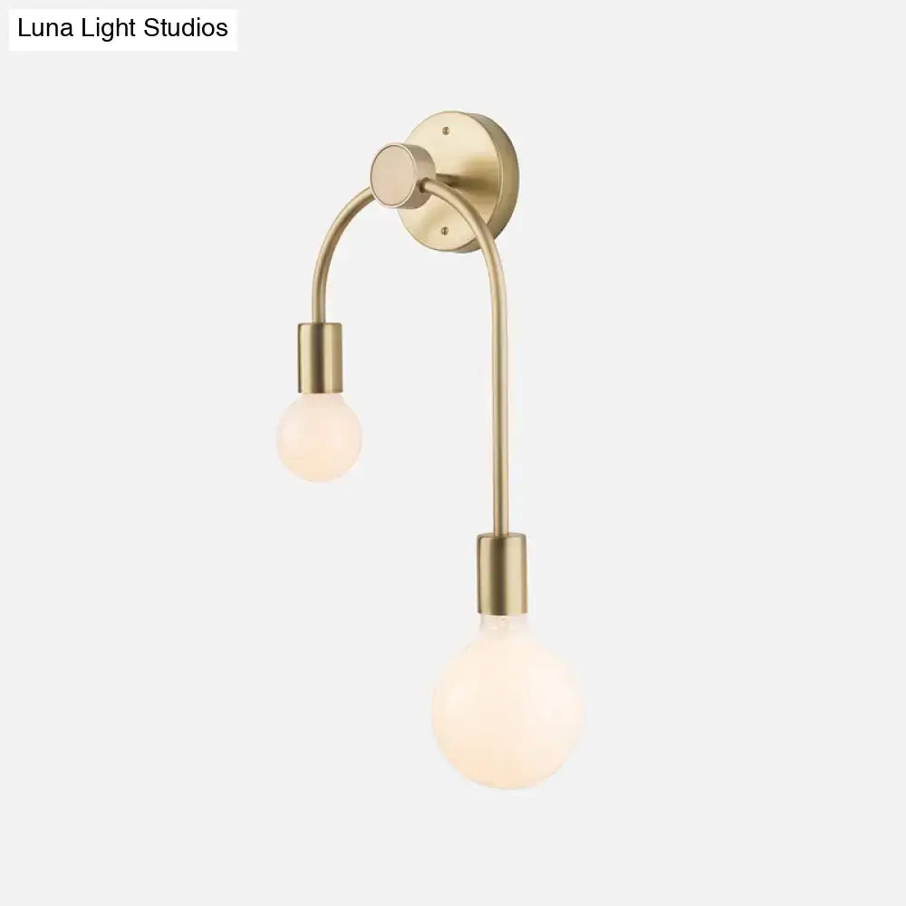 Brass-finished wall lamp with two curved arms holding frosted glass globe bulbs for minimalist bedroom decor