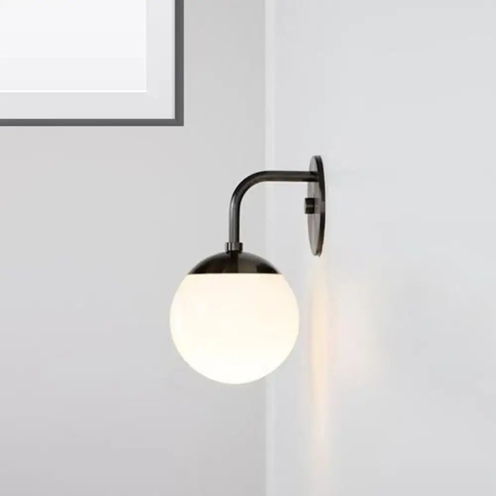Minimalist black metal wall light with frosted milky glass ball and gold accents for bedroom lighting