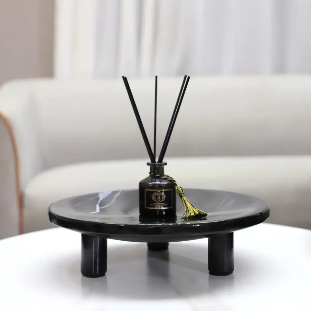 Black glass reed diffuser with gold tassel and slender black reeds displayed with decorbites imitation marble fruit tray decor