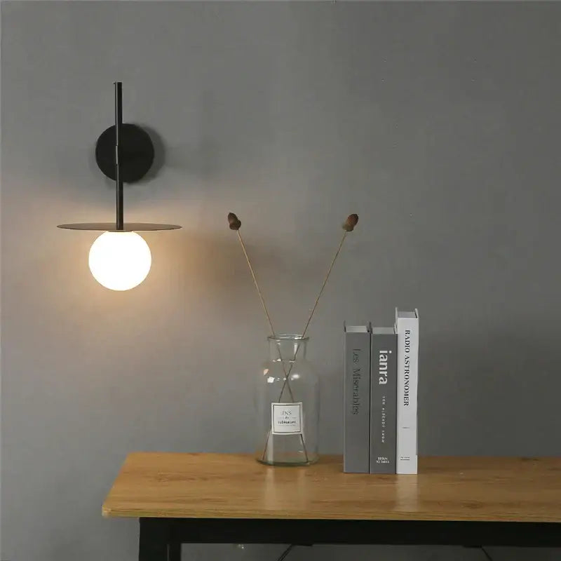 Minimalist black iron glass led wall light with circular base and glowing bulb for bedroom living room decorbites wall light