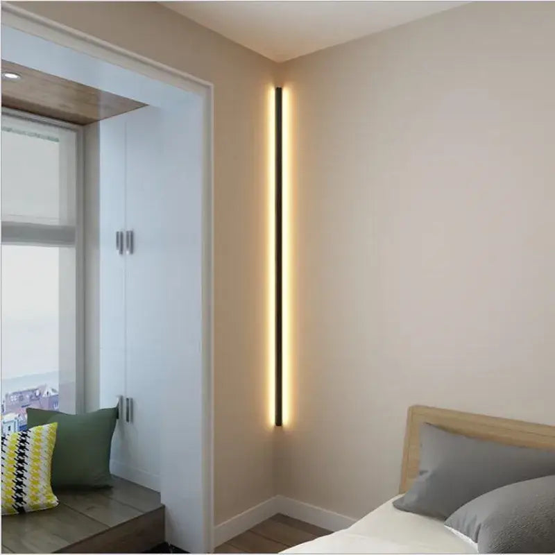 Minimalist black linear led wall lamp with warm glow mounted vertically in a modern bedroom corner