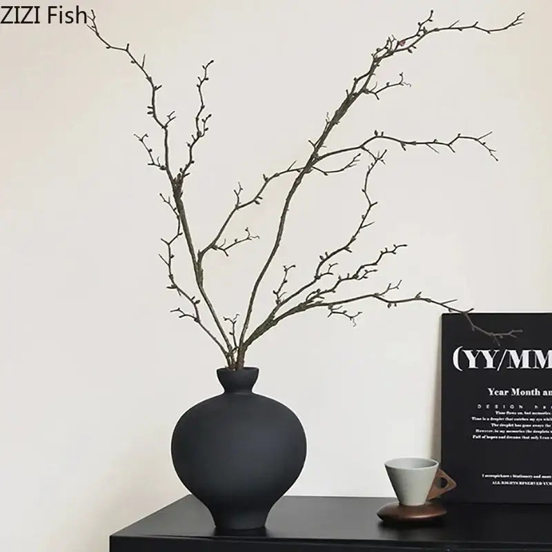 Minimalist black matte big belly ceramic vase with slender branches arranged for living room decor