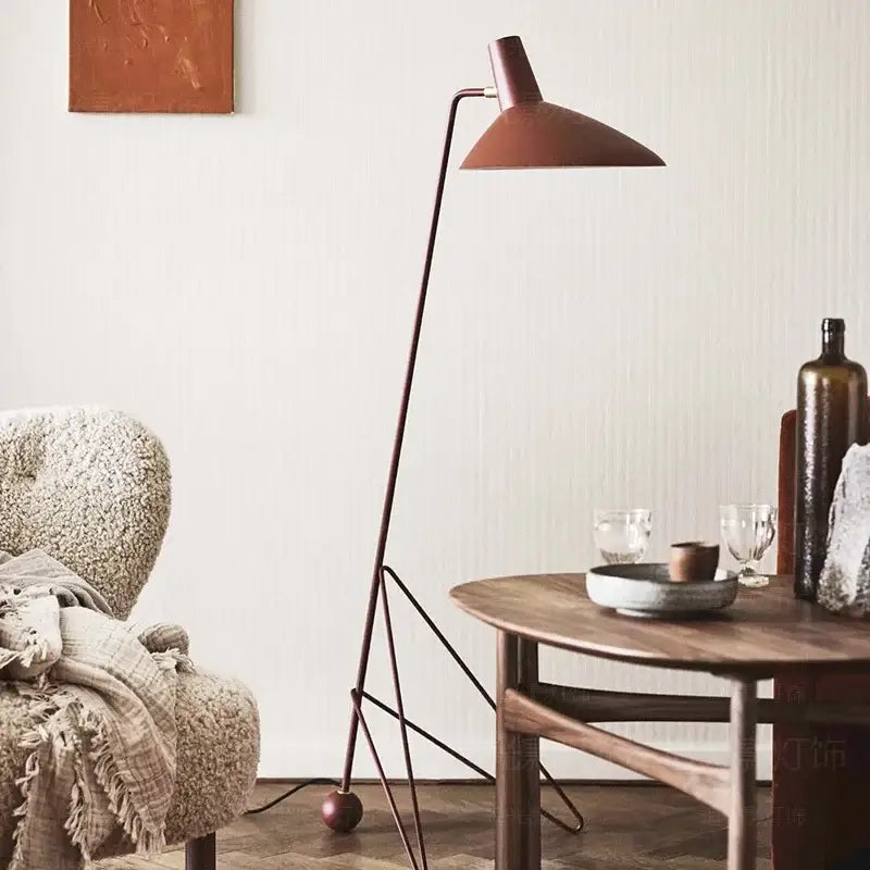 Minimalist black metal tripod desk lamp with a matte terracotta shade for bedroom or office use