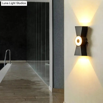 Modern black metal wall sconce with warm white light and geometric design for minimalist bedroom fixtures