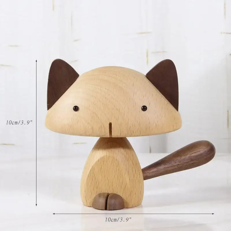 A minimalist wood carving figurine of a light wood cat with black bead eyes and dark brown ears tail and paws for living room decor