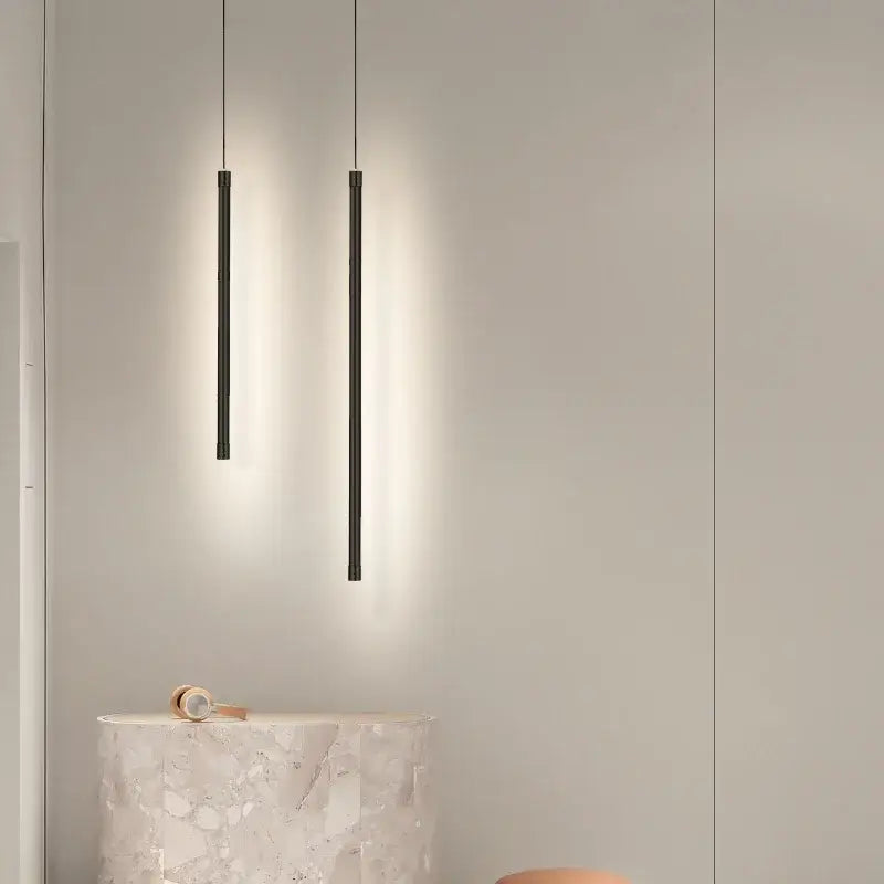 Two sleek black cylindrical decorbites black nordic led pendant lights hanging in kitchen dining room decor