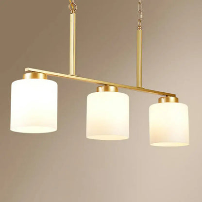 Gold-toned pendant island lighting fixture with three opal frosted glass shades and a metal frame hanging light