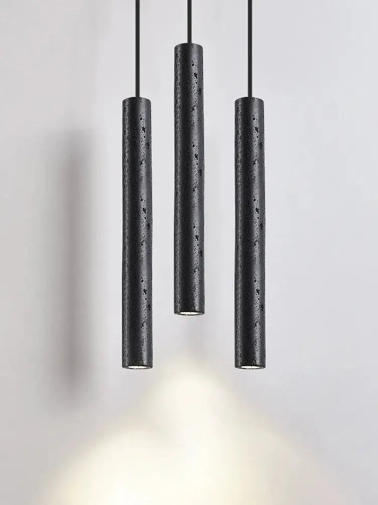Three black stone tube led pendant lights with a textured finish hang from cords for minimalist bedroom decorbites lighting