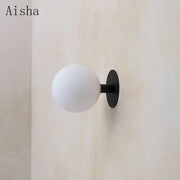 Minimalist black wall lamp with a frosted white glass globe lighting fixture by Aisha brand for bedroom decorbites gold