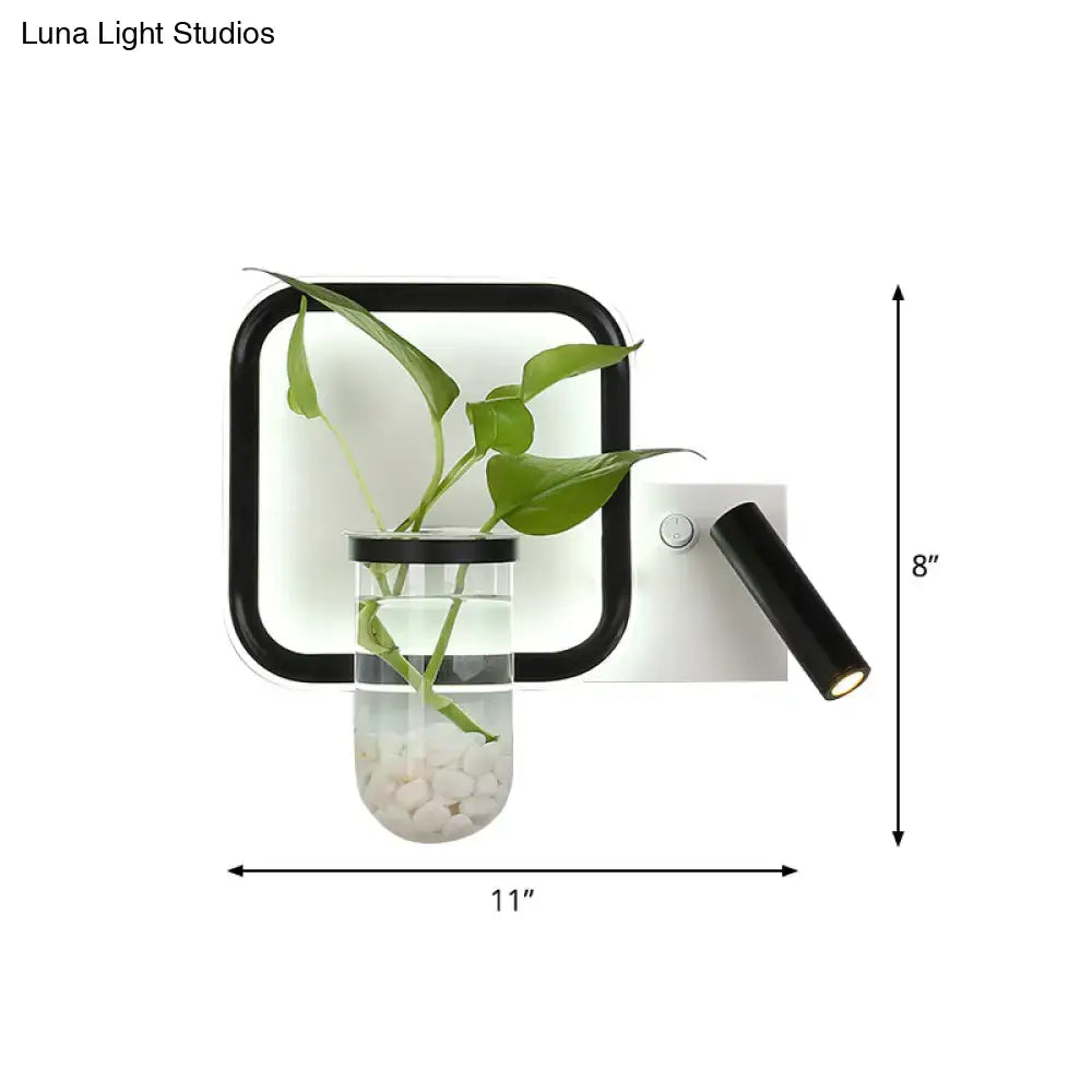 Minimalist black wall mount light with glass plant pot, clear vase with green leaves and adjustable spotlight for bedroom
