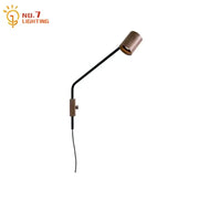 A sleek black wall lamp with a wooden cylindrical head and walnut swing arm for minimalist bedroom decor
