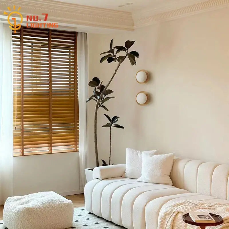 Cream-colored tufted fabric sofa next to minimalist black walnut wall lamp for bedroom and living room decorbites black walnut