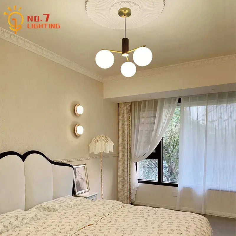 Modern brass-finished chandelier with three spherical white glass shades paired with minimalist decorbites black walnut wall lamp
