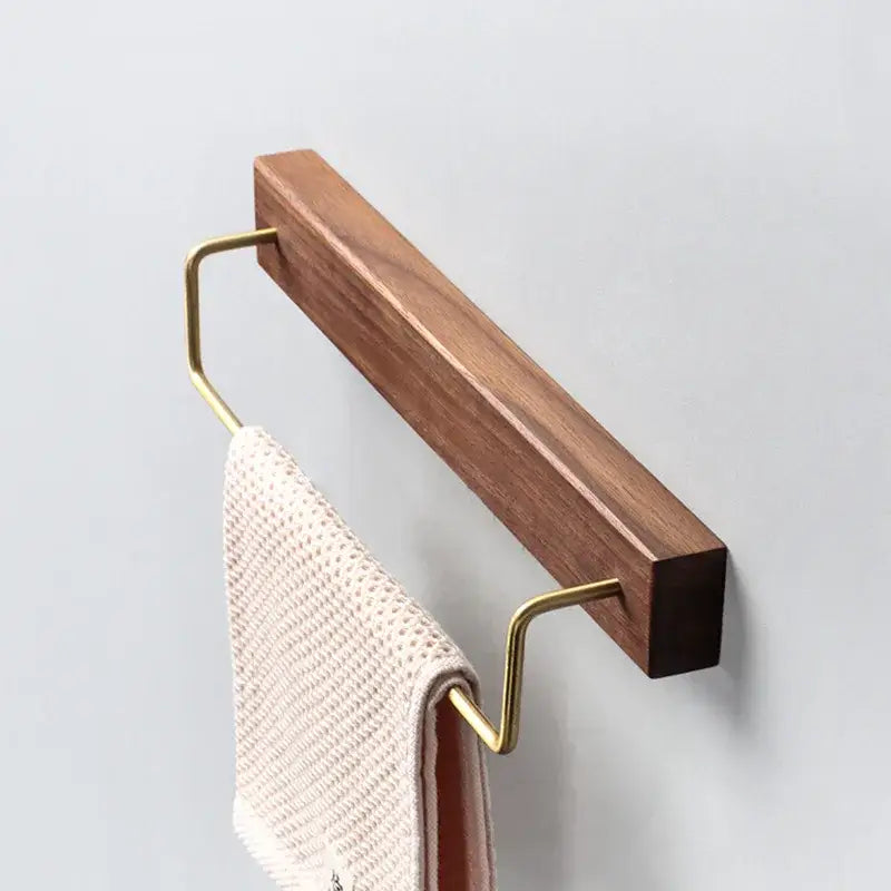 A sleek minimalist wall-mounted towel rack with black walnut wood and polished brass u-shaped hooks for bathroom use