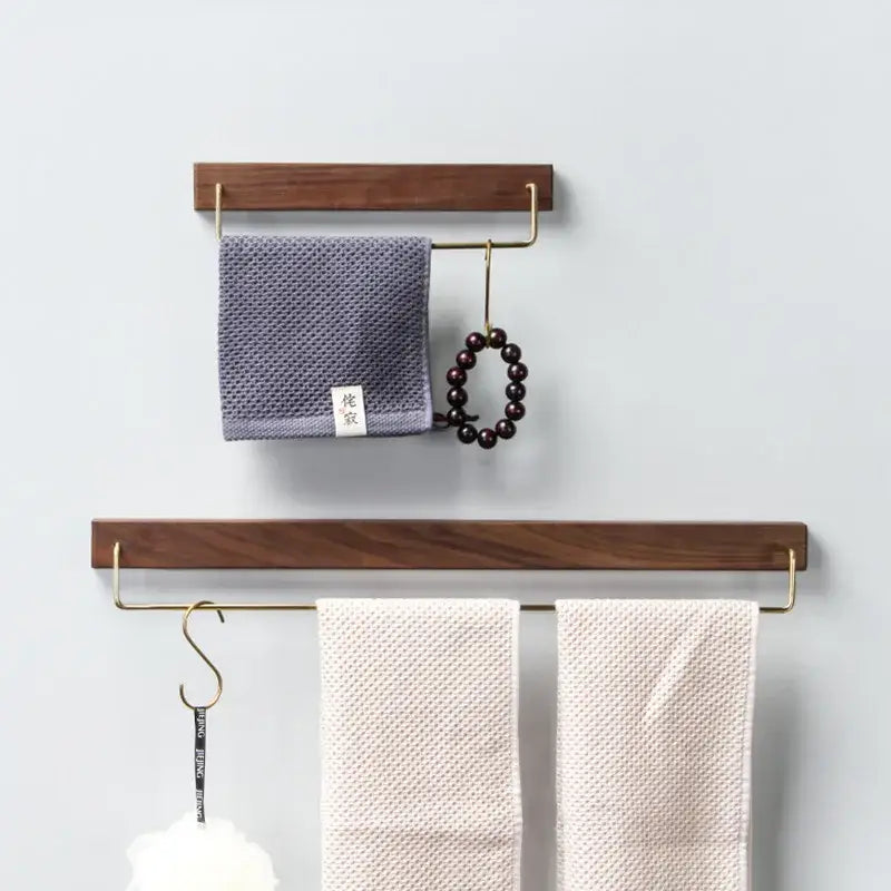 Minimalist black walnut wood towel rack 2 pack with brass accents holding gray and cream towels and a beaded bracelet