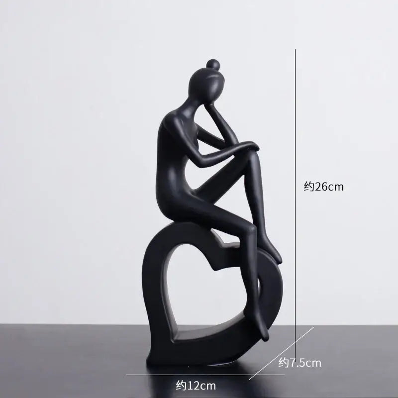 Minimalist black decorbites abstract resin sculpture of a glossy seated figure on a heart-shaped base for living room decor