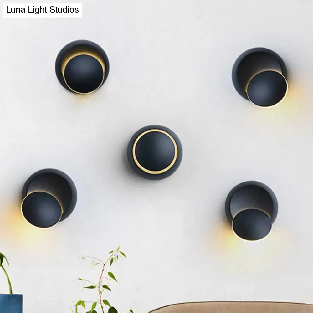 Minimalist black and white circular led wall lamp with black spherical sconces and gold rings emits warm ambient glow