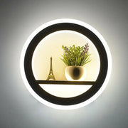 Minimalist black and white circular led wall sconce with shelf featuring a glowing led ring holding decorative items