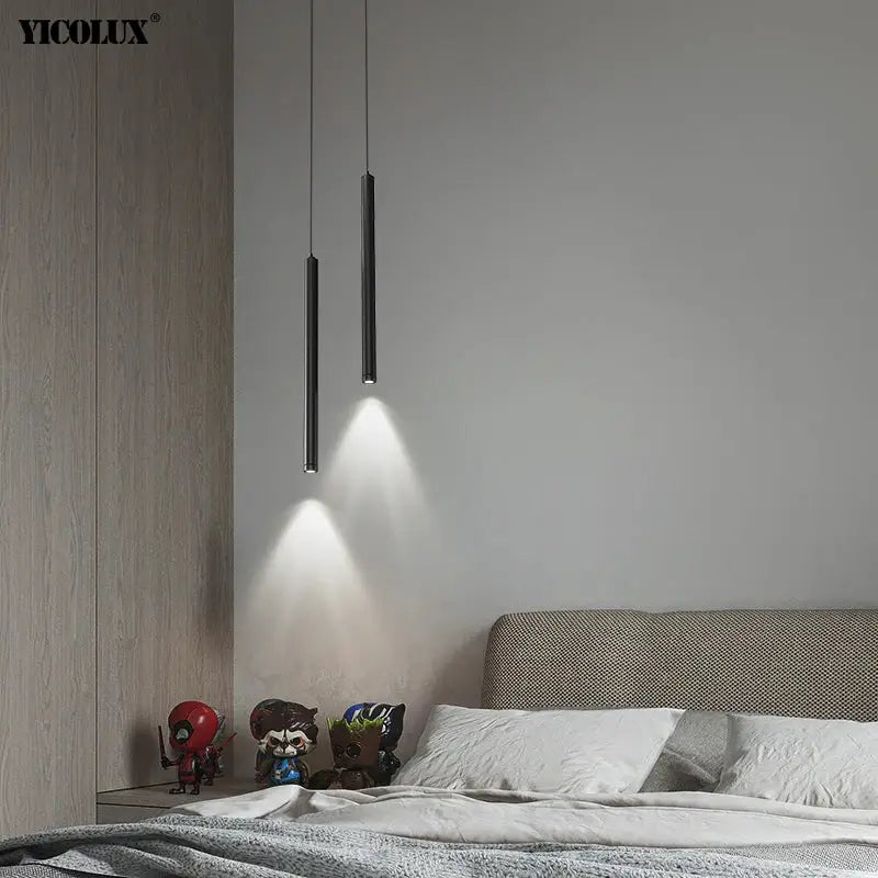 Two sleek black modern pendant lights hang from the ceiling casting focused light in a minimalist dining room