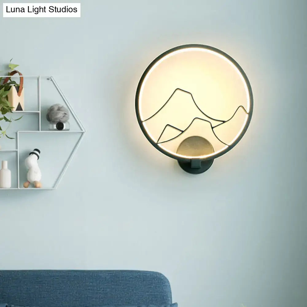 Minimalist black acrylic ring wall lamp with warm white illumination and mountain silhouette for bedroom lighting