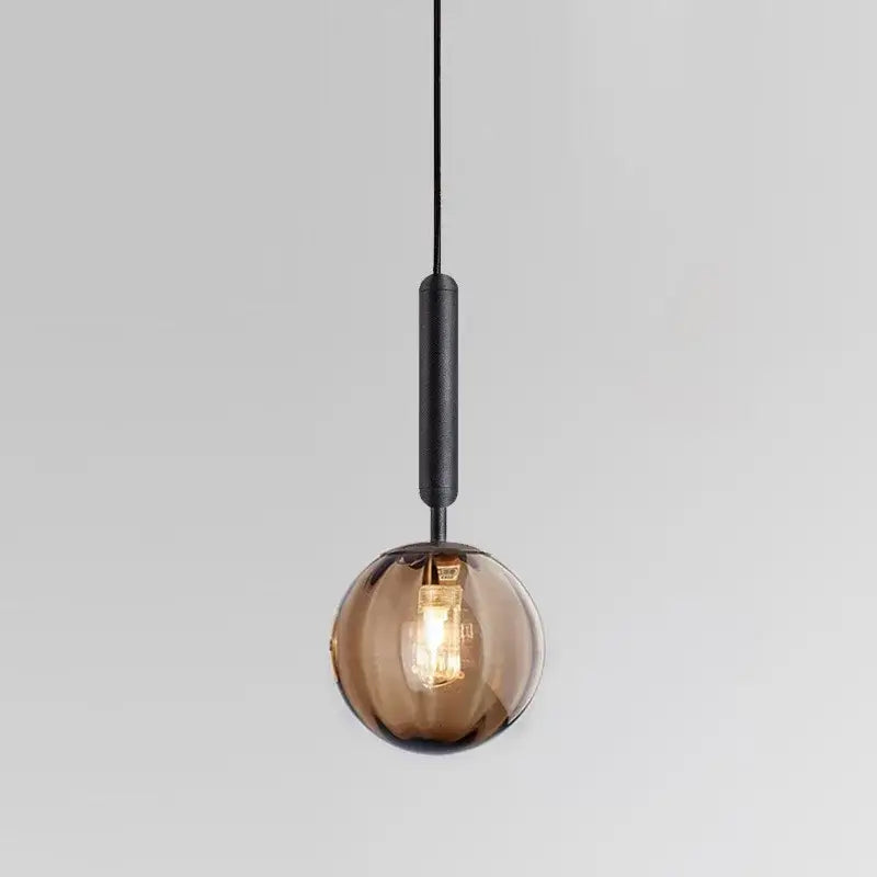 A minimalist amber-tinted decorbites glass ball pendant light with matte black stem for living room decor