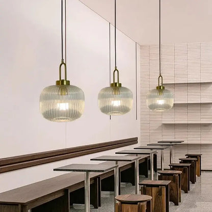Three elegant brass-finished pendant lights with clear glass ribbed globes for minimalist cord pendant installation