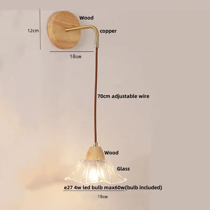 Minimalist brass wall light with clear glass bell shade and natural wood backplate featuring adjustable copper wire decorbites clear glass