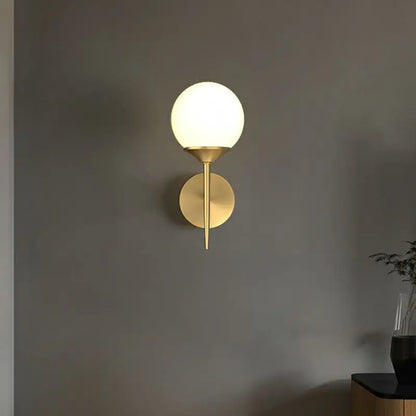 A sleek minimalist brass led wall lamp with frosted glass globe ideal for modern dining room lighting