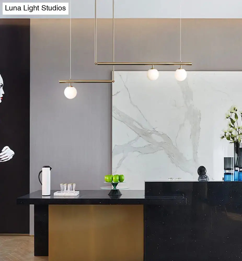 Minimalist brass ceiling light with slender gold rods and white globe glass bulbs for kitchen island lighting