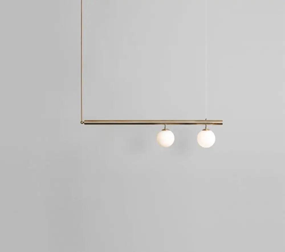 Minimalist brass ceiling light with two white globe glass bulbs designed for kitchen island lighting