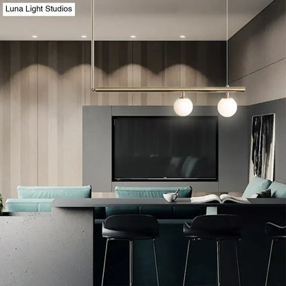 Minimalist brass ceiling light with white glass globe bulbs designed for kitchen island lighting