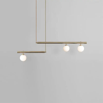Modern minimalist brass ceiling light with three white globe glass bulbs designed for kitchen island lighting