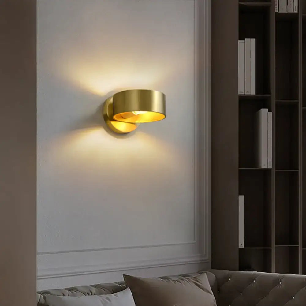 Brass-finished minimalist wall lamp with curved cylindrical design casting warm light for 110v-120v use