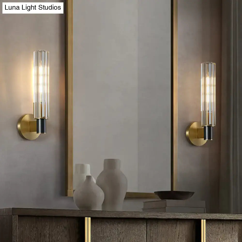 Minimalist brass finish tubular wall light sconce with gold-toned metal, clear glass tubes, and black accents for bedroom use