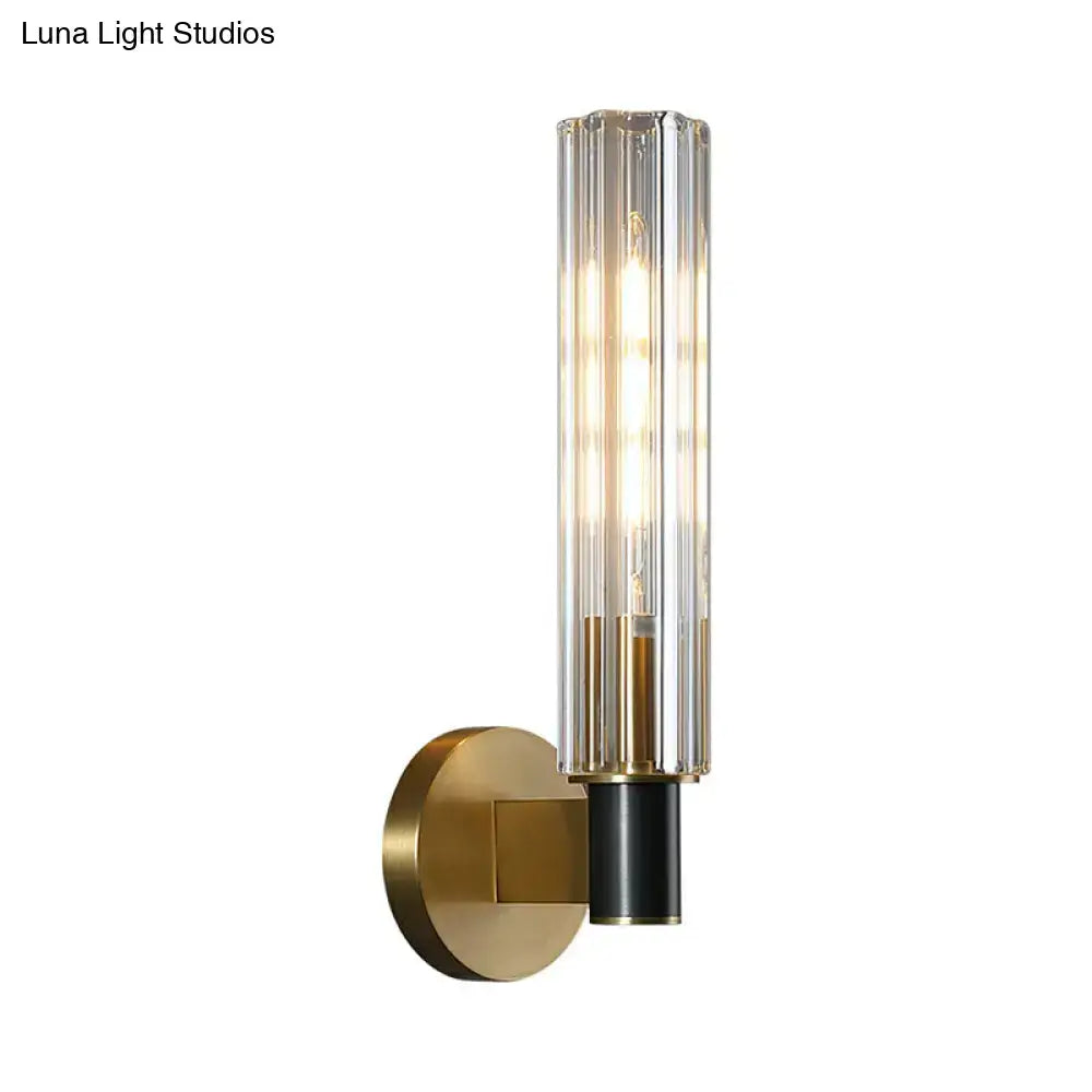 A minimalist brass finish tubular wall light sconce with gold metal base and ridged glass shade for bedroom use