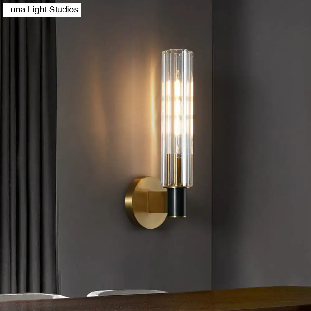 Minimalist brass finish tubular wall light sconce with clear vertically ribbed glass cylinder for bedroom lighting