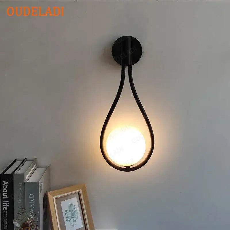 Minimalist black metal decorbites brass glass teardrop wall sconce with warm glowing bulb for living room light