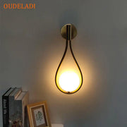 Minimalist brass glass ball wall sconce with a warm glowing bulb in teardrop shape for living room decorbites brass glass