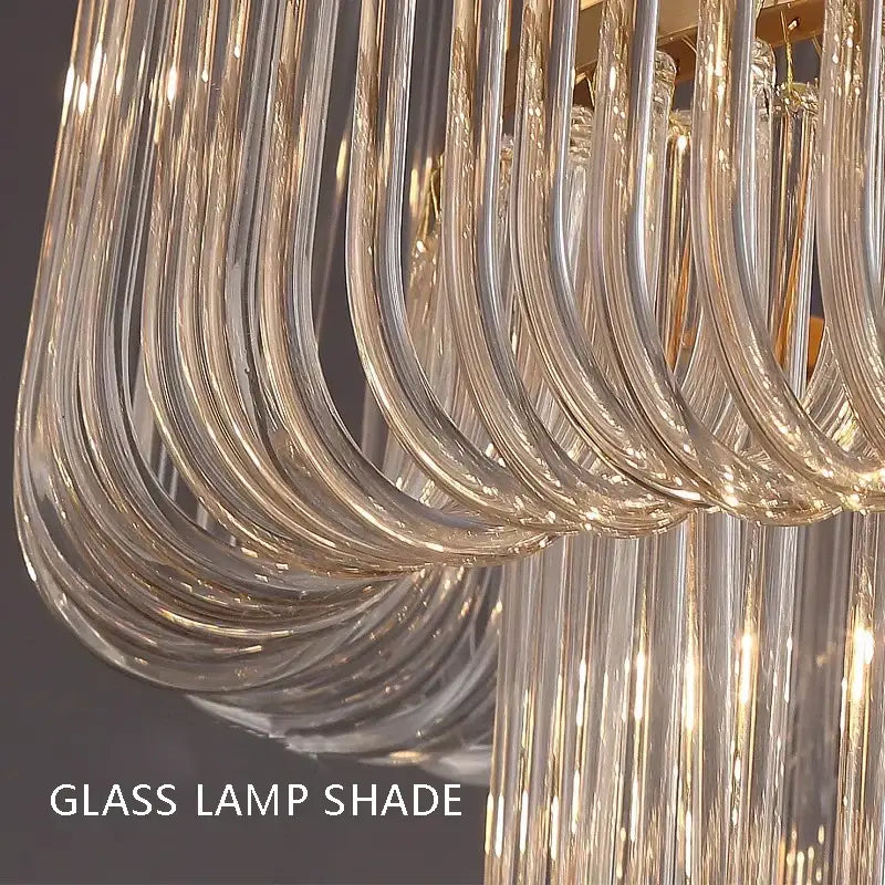 Curved transparent glass lamp shade with gold-toned accents in minimalist brass glass bar chandelier decorbites design