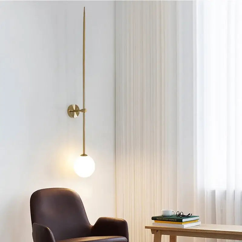 Minimalist slender brass led wall light with frosted globe bulb ideal for bedroom wall lights