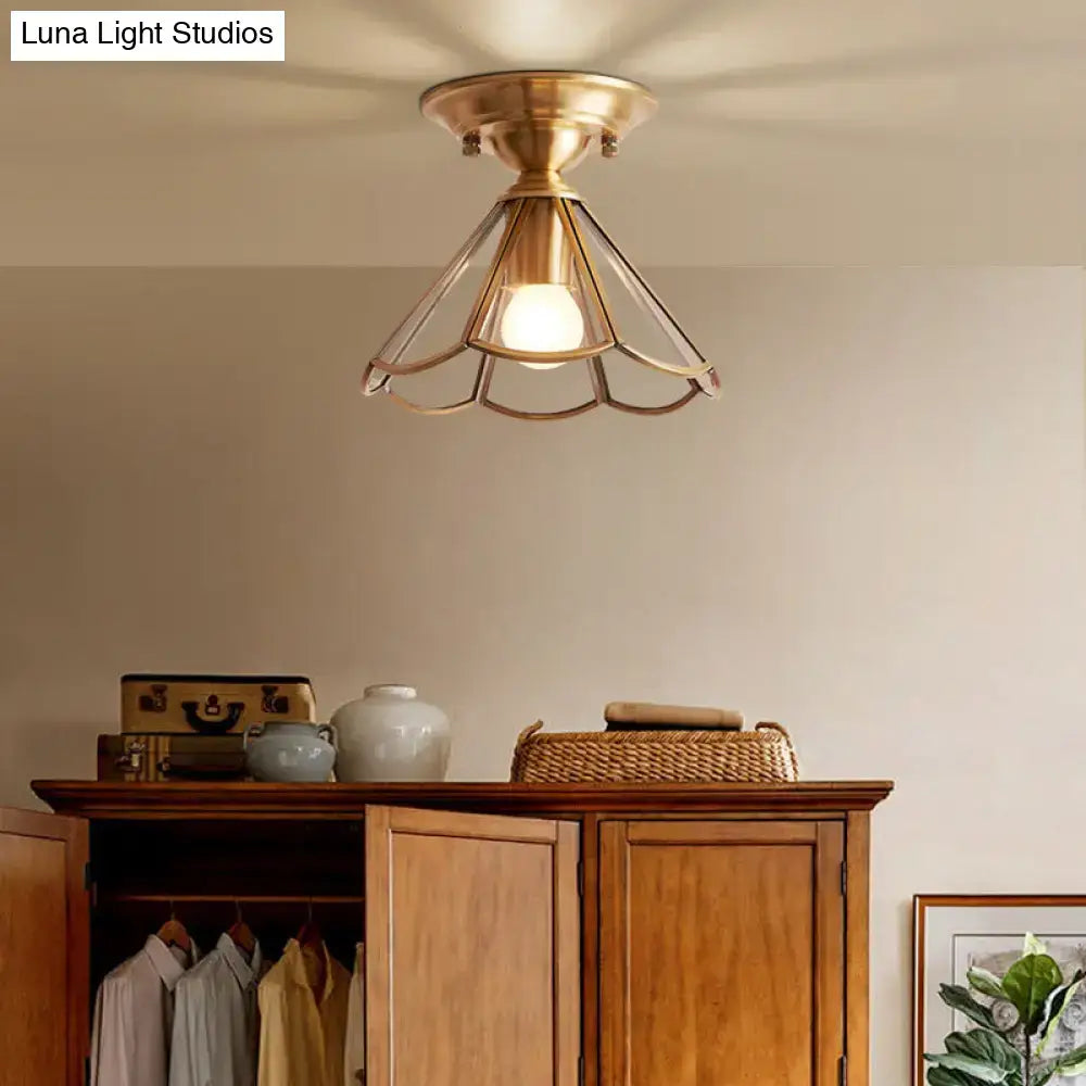 Brass-finished industrial-style flush mount ceiling light with geometric cage design and warm single bulb flush glow