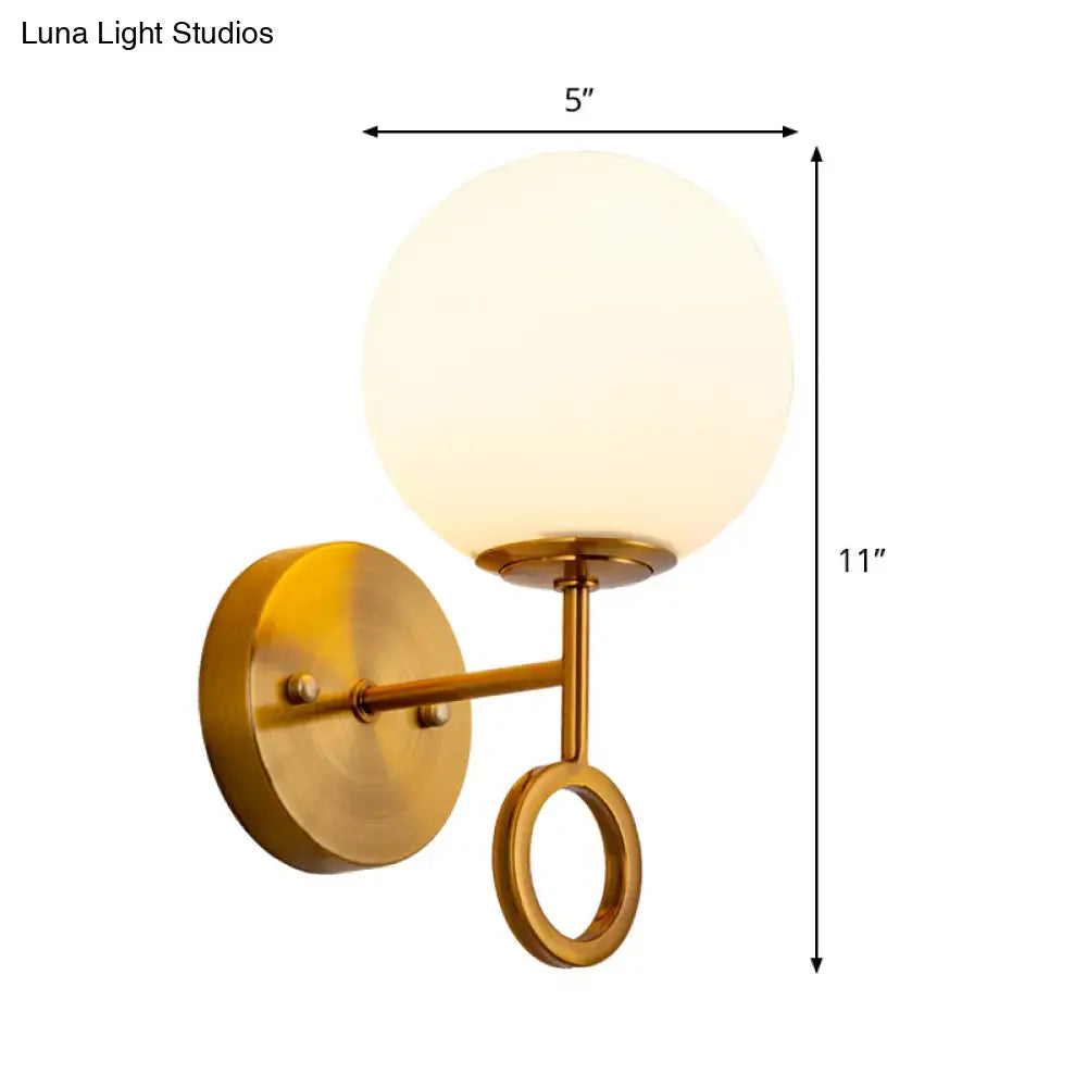Minimalist brass wall sconce with cream glass shade and ornamental ring accent for bedroom lighting