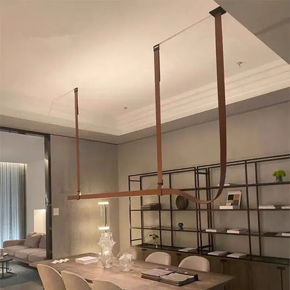 Modern copper-toned pendant lamp with sleek curved metal arms for minimalist brown leather hanging clothes drying rack decorbites belt