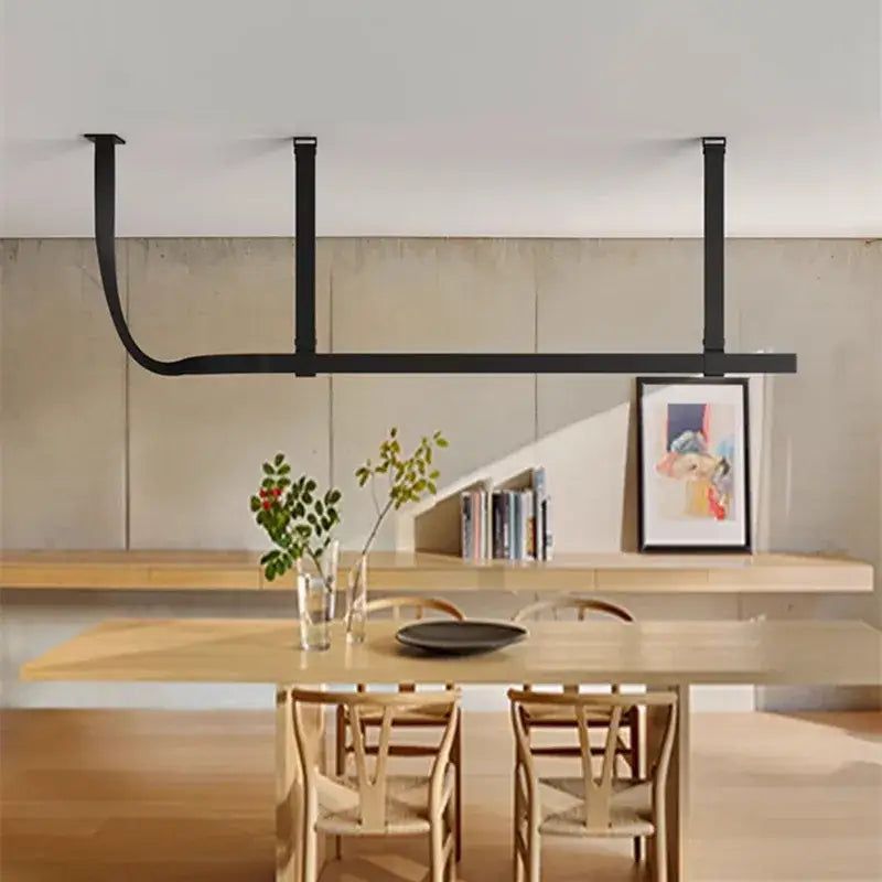Black metal pendant lamp with minimalist design suspended above wooden table complements decorbites belt decor