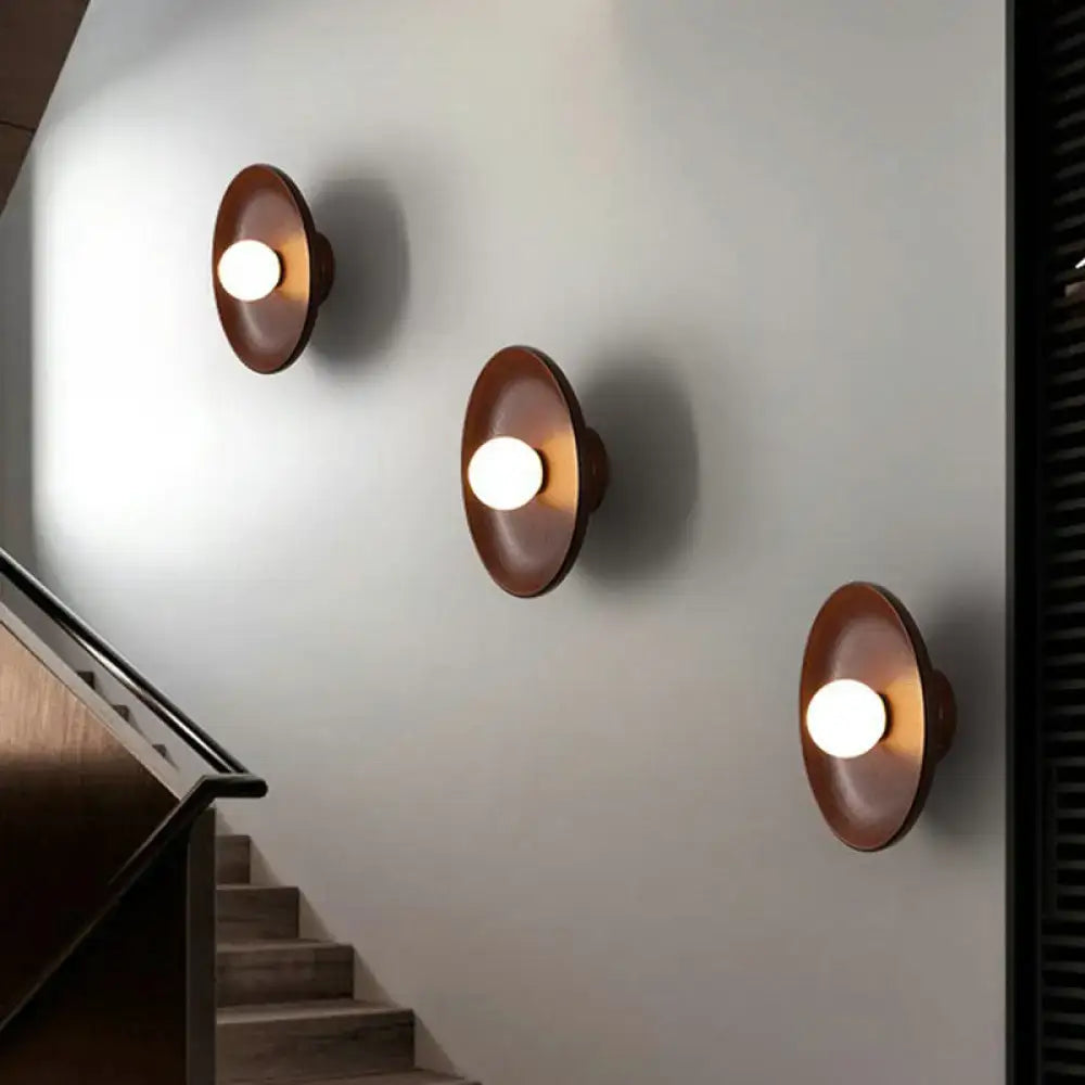 Three copper-toned minimalist wall light fixtures with circular shades and warm glowing bulbs for living room use