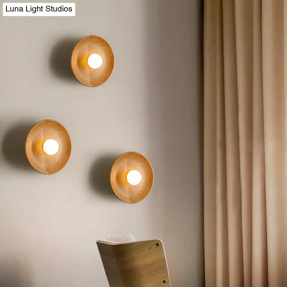 Three warm-toned circular wooden wall light sconces with smooth natural finish and minimalist brown wood fixture height for living room