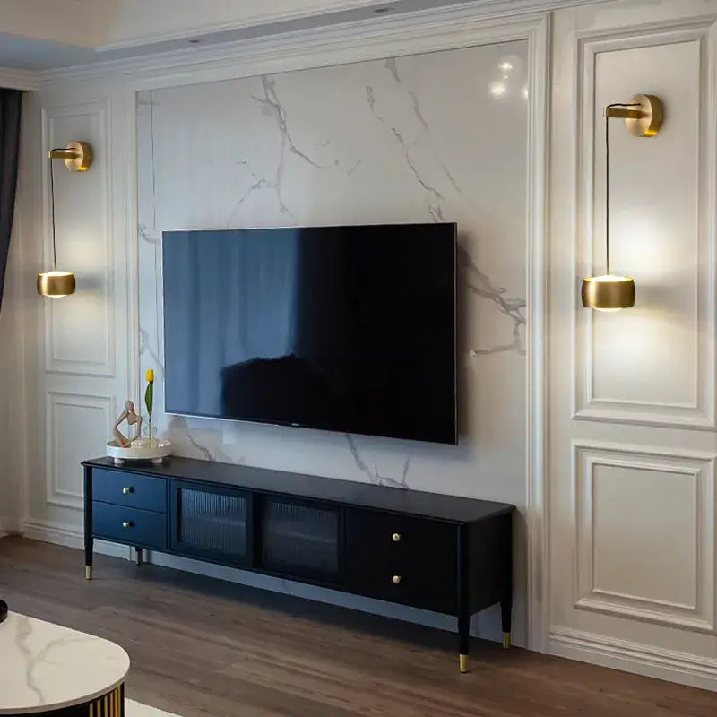 Black tv stand with gold tone legs and drawers complements minimalist brushed brass and matte black wall lamp decorbites copper adjustable design against marble wall background