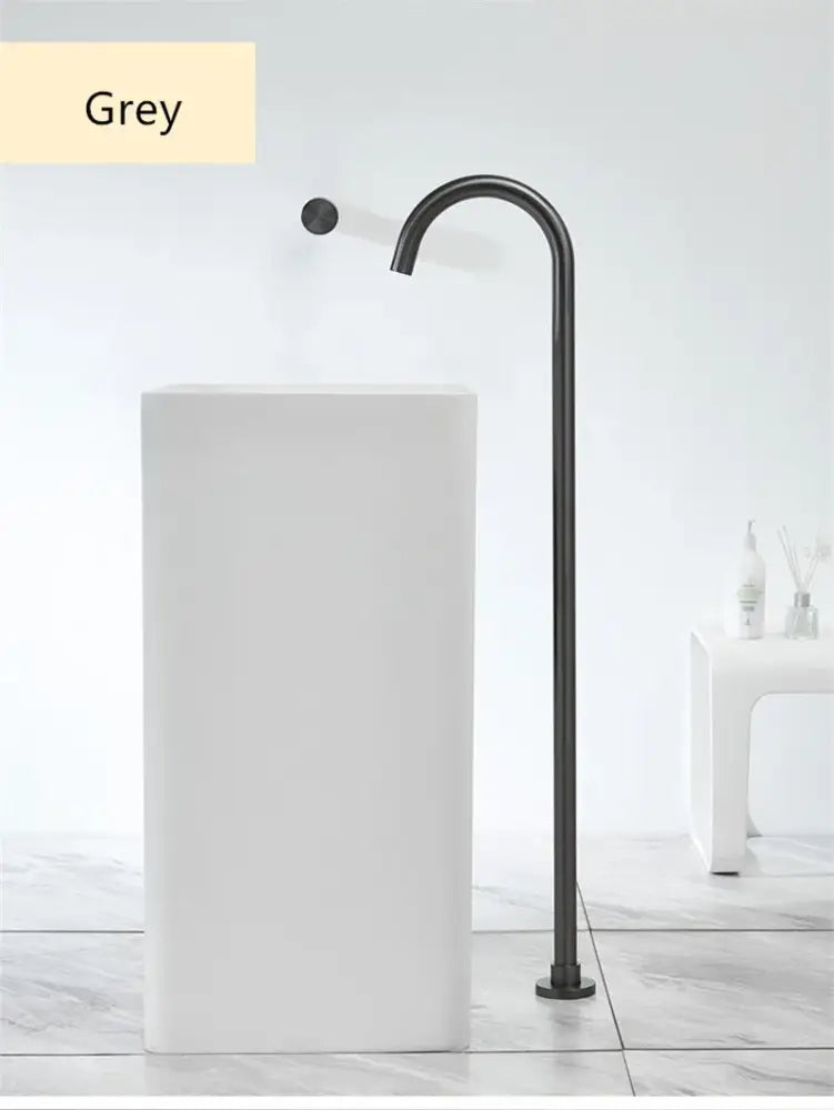 Modern minimalist freestanding sink with white ceramic body and matte black faucet paired with brushed gold bathtub shower faucet