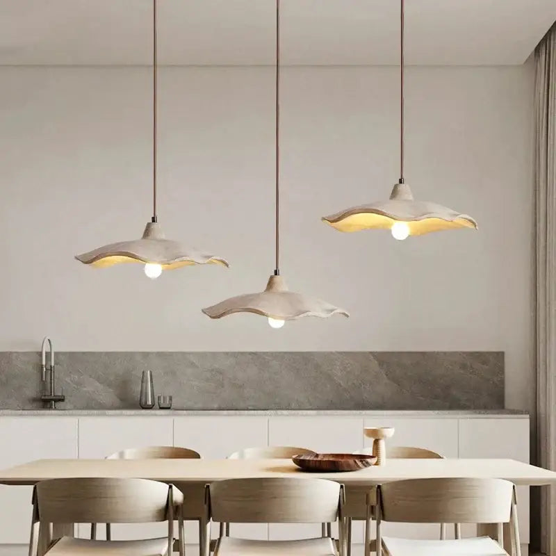 Minimalist off-white ceramic petal pendant chandelier with scalloped edges hanging from concrete ceiling decorbites